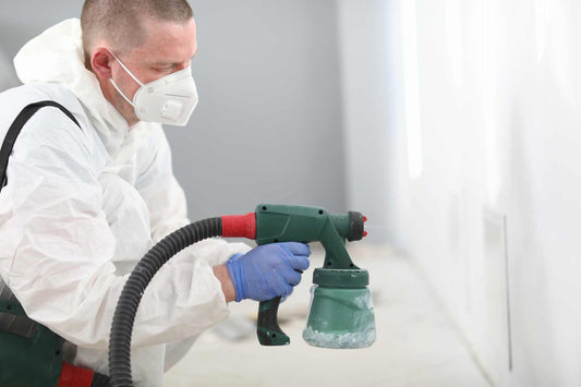 A person wearing a mask while painting a wall