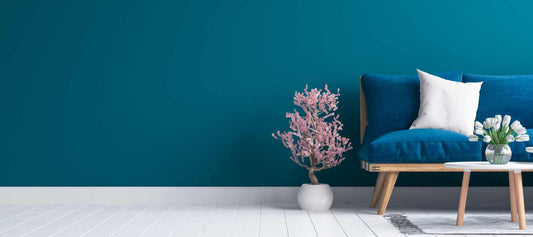 Room with a blue wall, couch with blue cushions, and a pink flowering tree