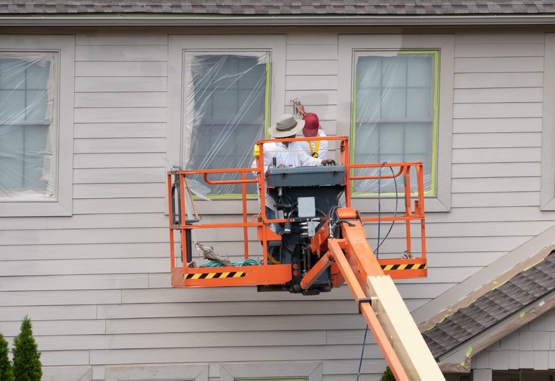 Two people painting the exterior of a new home 